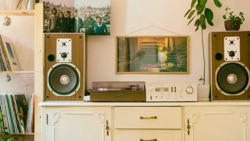 Retro glasbeni kotiček z vinilno zbirko, zvočniki, gramofonom in ojačevalcem na vintage omarici.