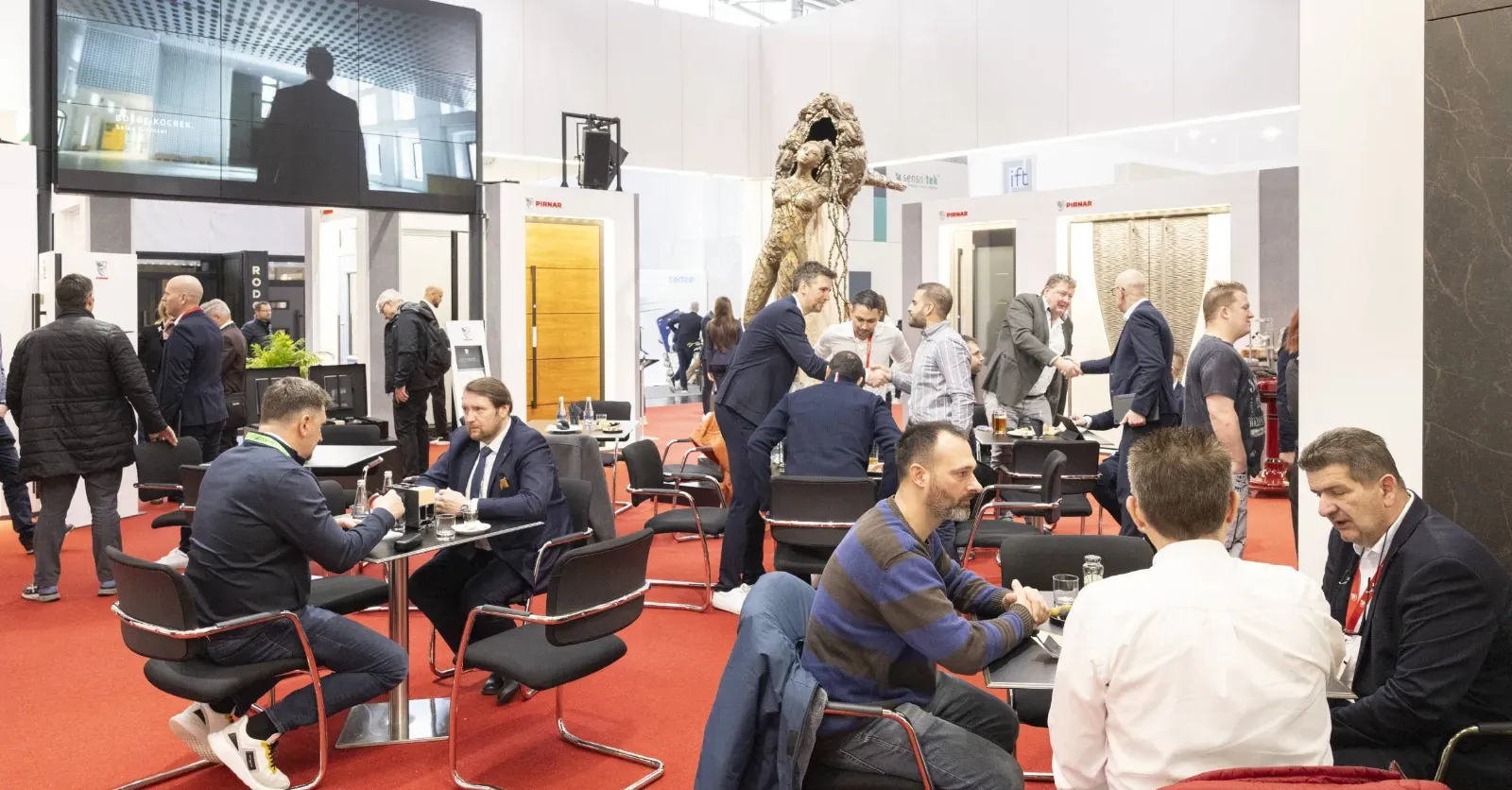 Na stojnici so vidne različne vrata in ljudje, ki se pogovarjajo ter sodelujejo.