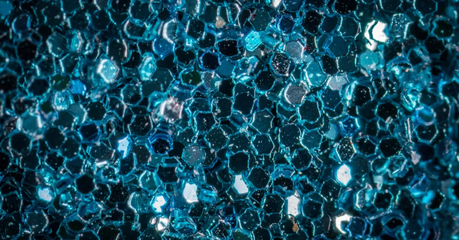 Na sliki so prikazani večbarvni šesterokotniki, ki tvorijo teksturo s svetlečimi in mat površinami.