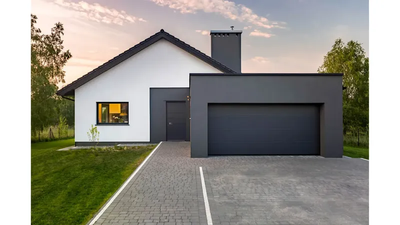 Pogled na hišo z dvema vrati, eno vhodnimi in eno garažnimi, obloženimi s temno barvo.