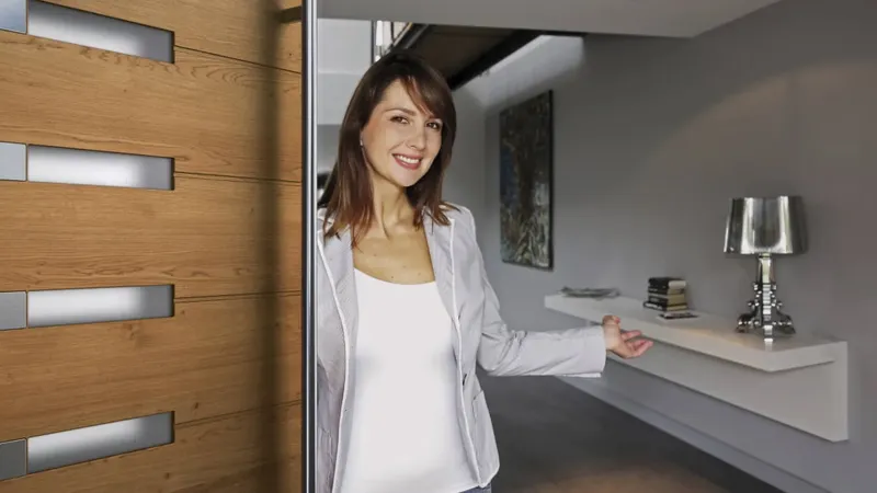 Vrata iz lesa z vgrajenimi steklenimi elementi, odprta proti notranjosti prostora.