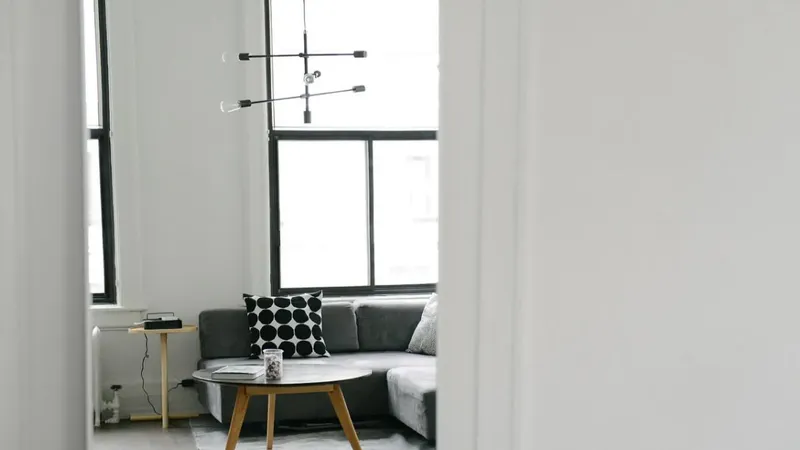 Pogled na dnevno sobo z oknom, sedežno garnituro in mizo.