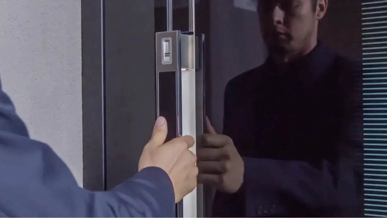 Moški odpira steklena vrata z ročajem.