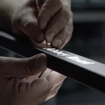 Roke nanašajo besedilo na črno leseno letvico.