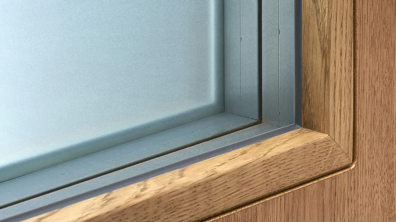 Vidna je lesena okvirna vrata z matirano steklo in kovinskim robom.