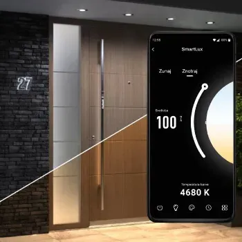 Vrata iz lesa z vertikalnim ročajem in številko hiše 27 ob steni iz temnega kamna.
