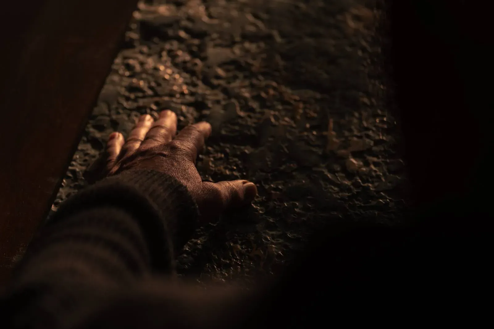 Roka se dotika površine, ki je videti groba in teksturirana.