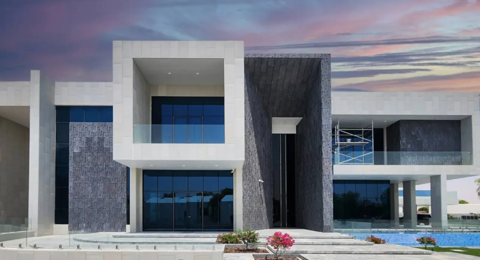 Pogled na vhodna vrata in steklene stene hiše z balkonom.